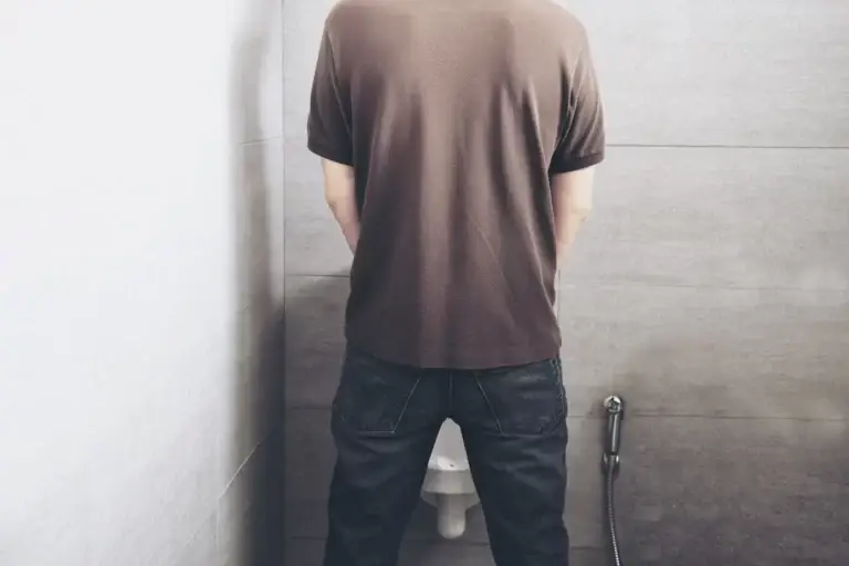 Homem de costas em um mictório.